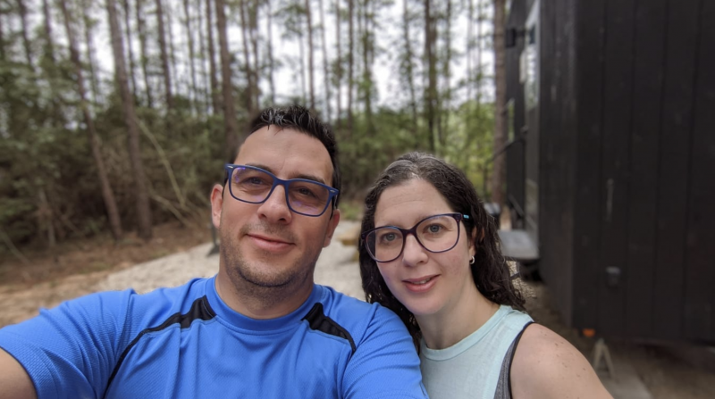 Carlos and Me with a background of trees and a cabin
