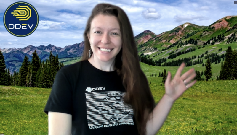 Long haired person in front of Colorado mountains on a greenscreen with the ddev logo